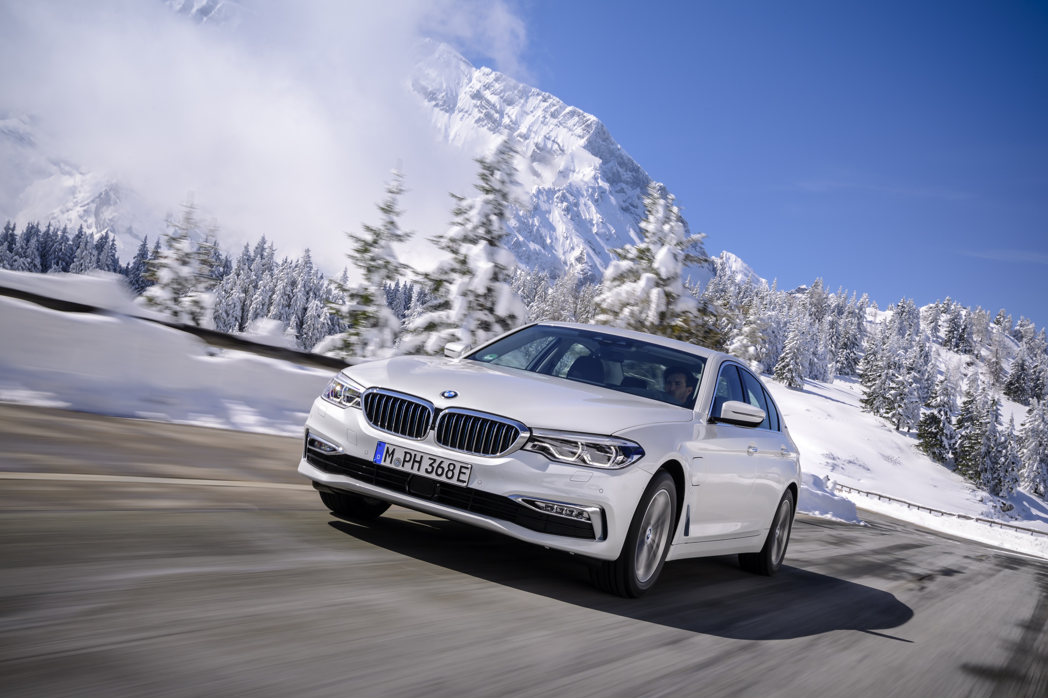 BMW 530e iPerformance plug-in hybrid sedan in white on a snow-lined road, the G30-generation model covered by recall 26V441000, the campaign whose starter relay can corrode and overheat and which carries a park-outside advisory