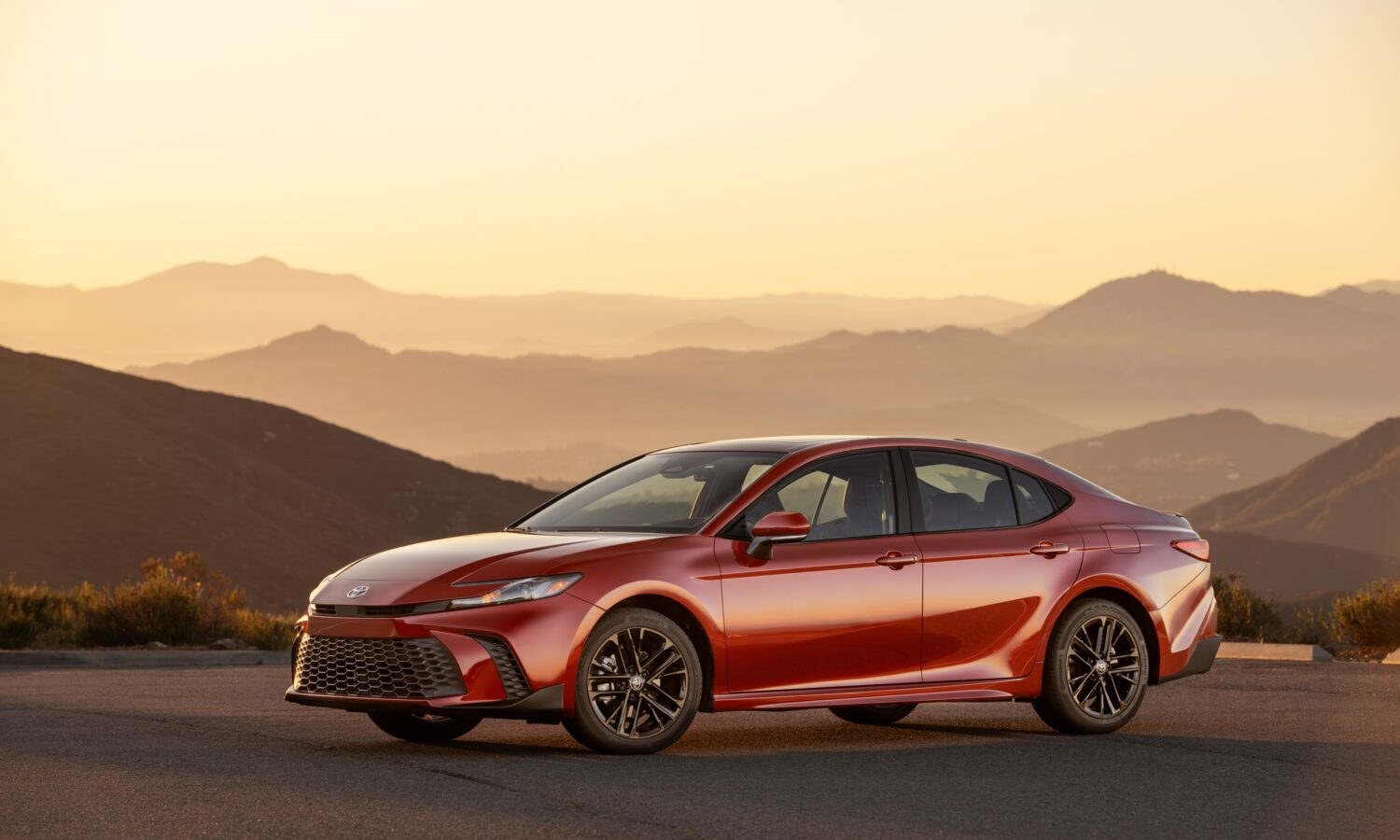 2025 Toyota Camry SE AWD in Supersonic Red, front three-quarter view, the hybrid-only generation covered by recall 26V511