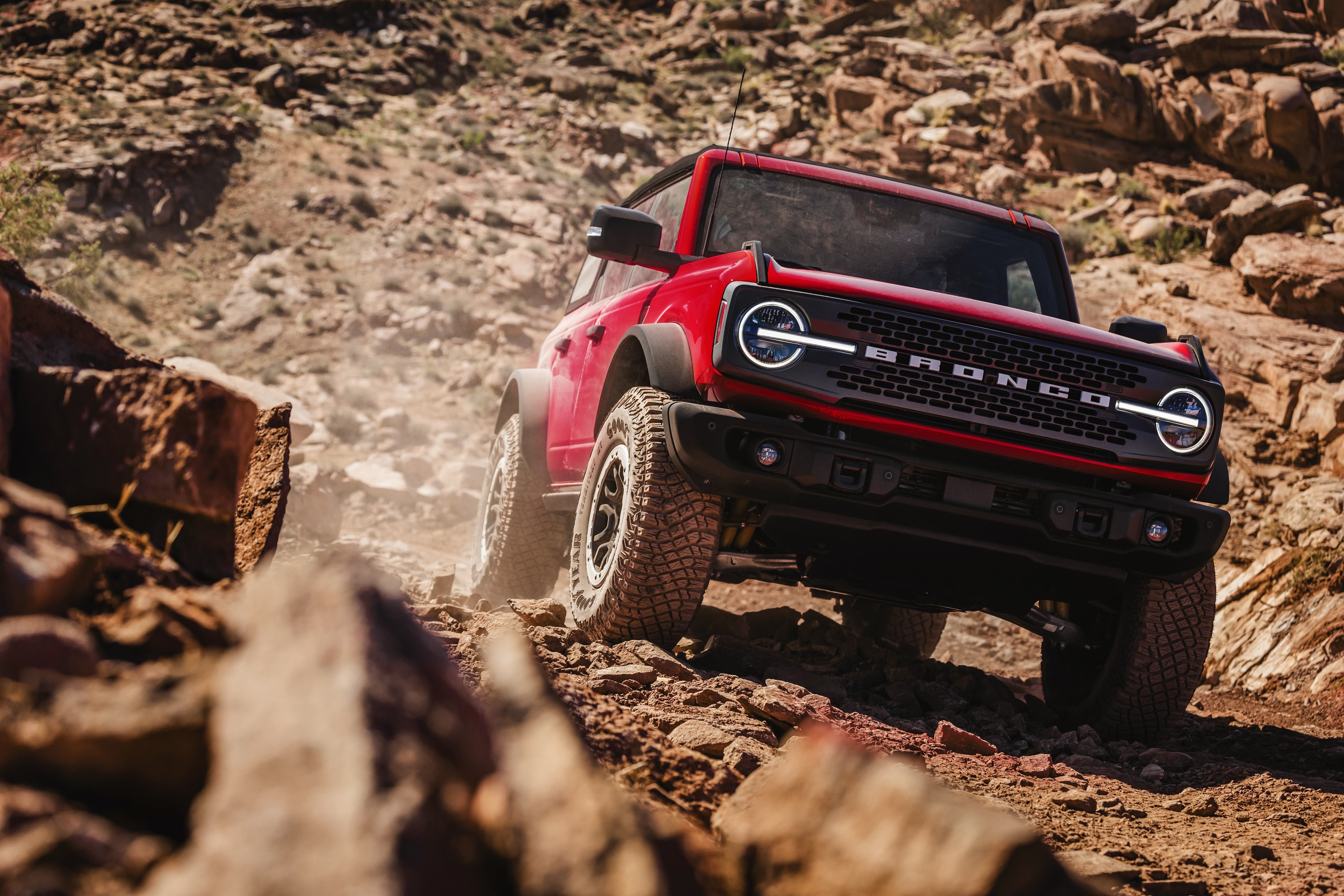 2026 Ford Bronco Badlands in Ruby Red descending a rocky trail, the same sixth-generation body style as the recalled 2021-2024 Broncos