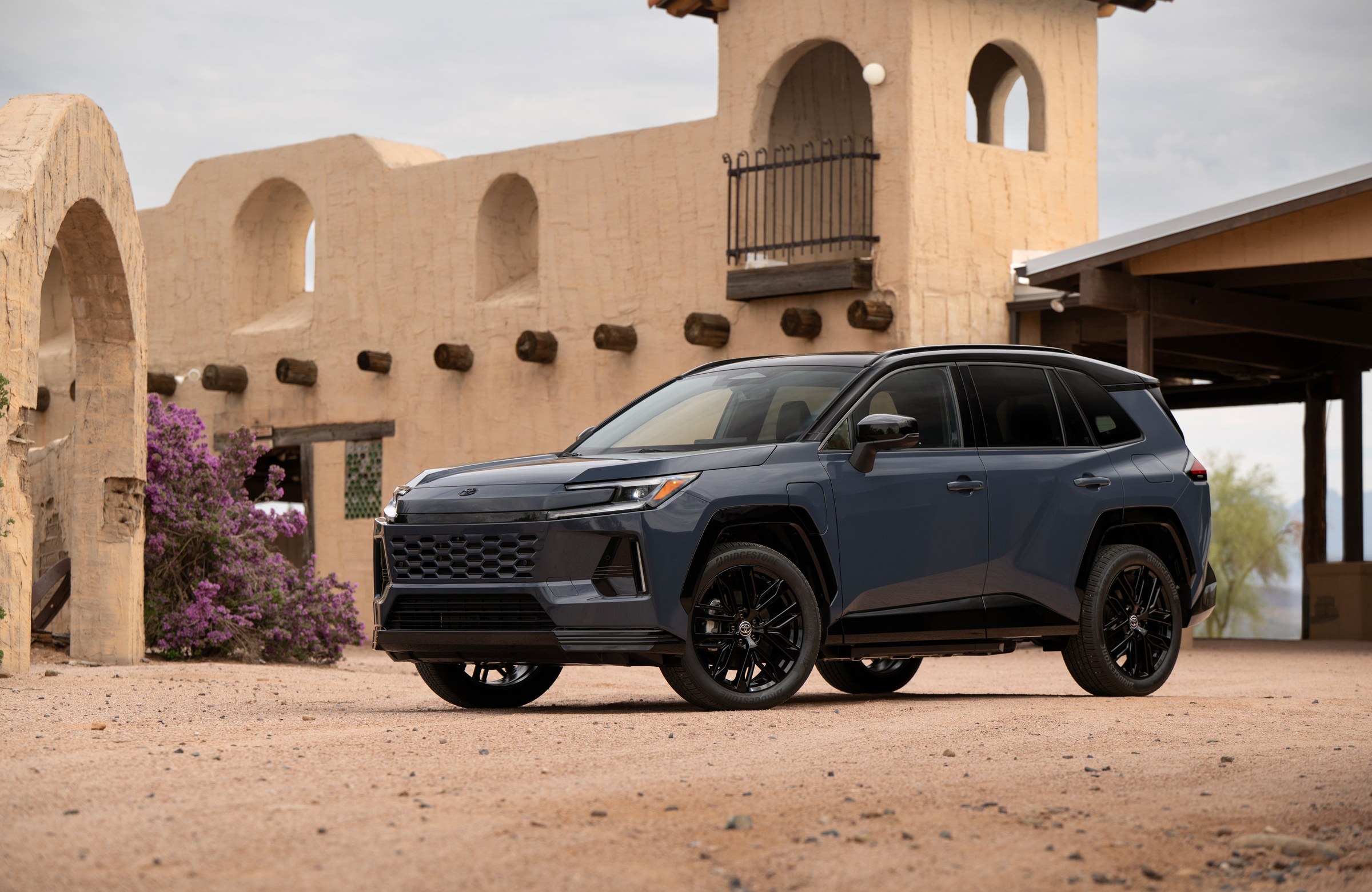 2026 Toyota RAV4 Plug-in Hybrid XSE in Storm Cloud with a black roof, front three-quarter view in front of an adobe building, the model recalled under campaign 26V659000 because a motor generator ECU software error can cut drive power