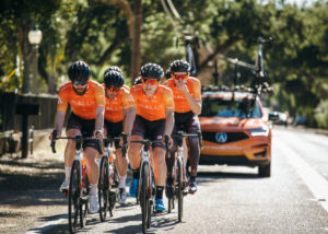 The Rally Cycling Team and its 2019 Acura RDX support vehicle in the background.