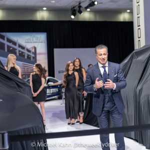 Porsche vehicles under black covers before a reveal on the Porsche stand at the LA Auto Show