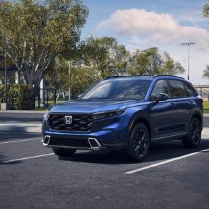 2026 Honda CR-V Hybrid Sport Touring AWD in blue exterior front three-quarter view parked at a park with sports fields in the background