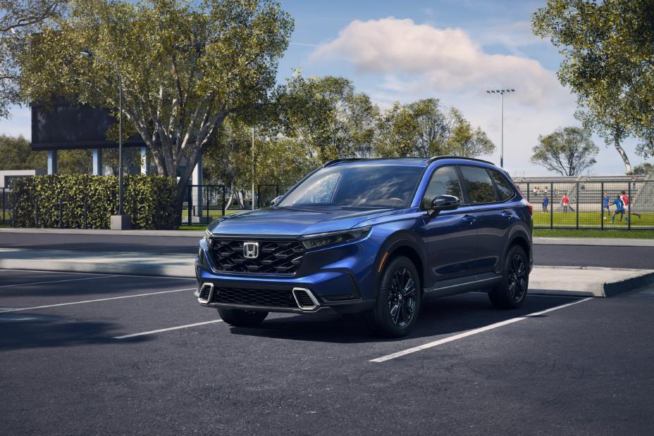 2026 Honda CR-V Hybrid Sport Touring AWD in blue exterior front three-quarter view parked at a park with sports fields in the background