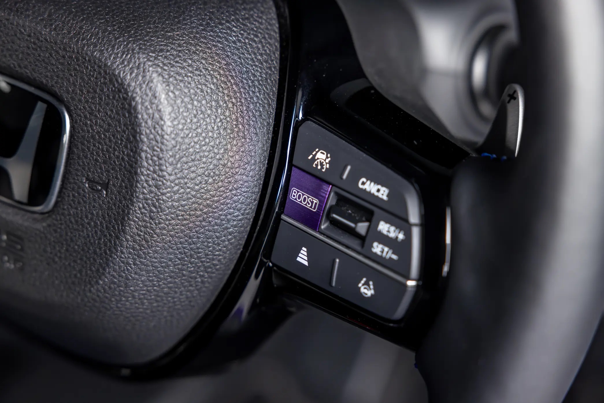 2026 Honda Super-N BOOST mode button close-up on the steering wheel spoke in iridescent purple