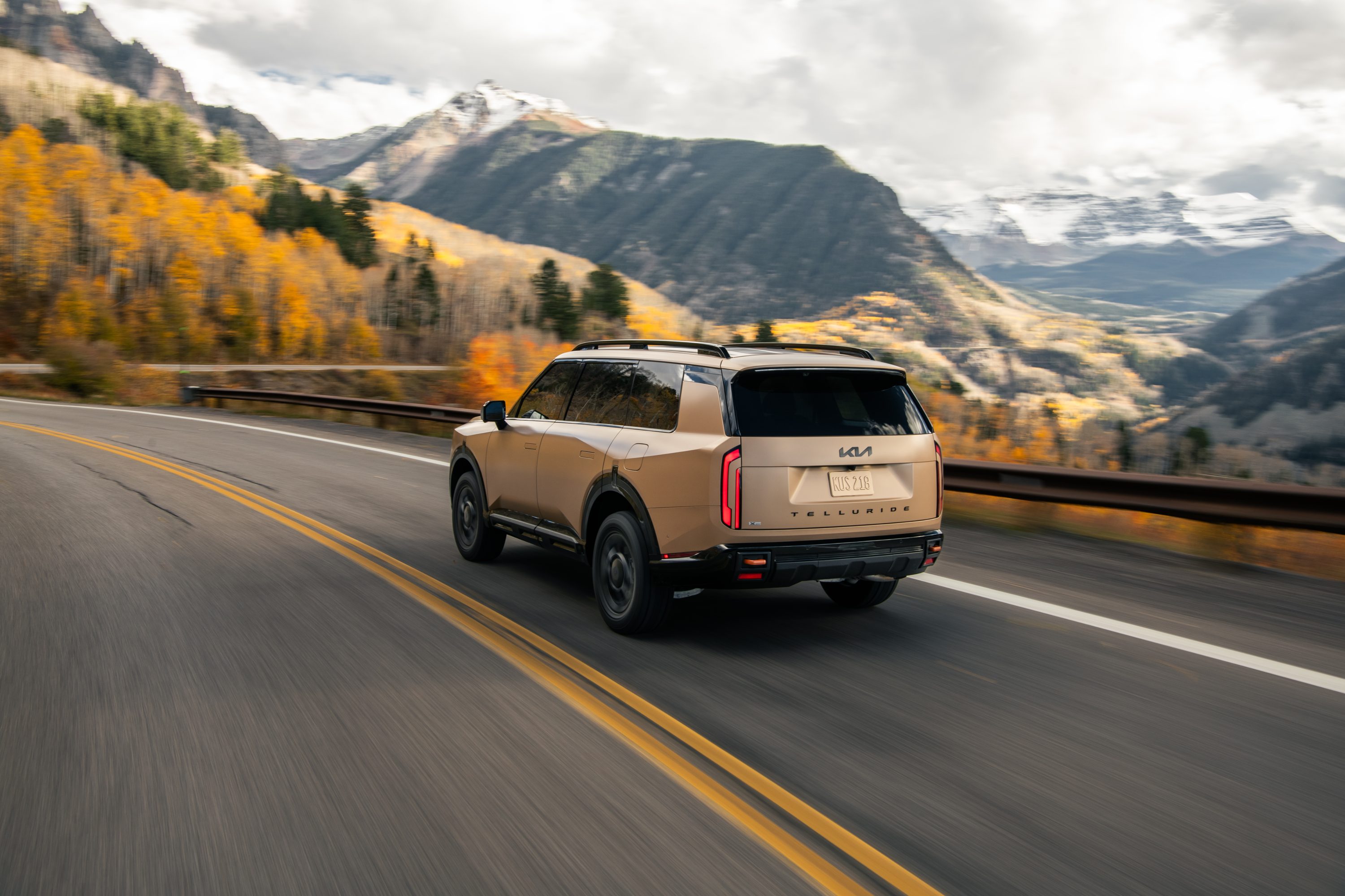 2027 Kia Telluride X-Pro rear three-quarter driving on a mountain road with fall foliage