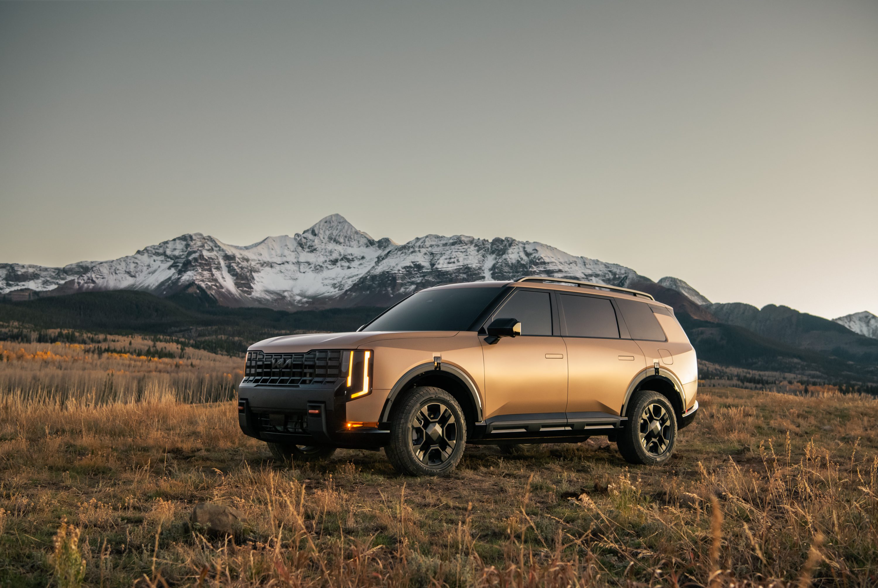 2027 Kia Telluride X-Pro parked in a meadow with snow-capped mountains behind it