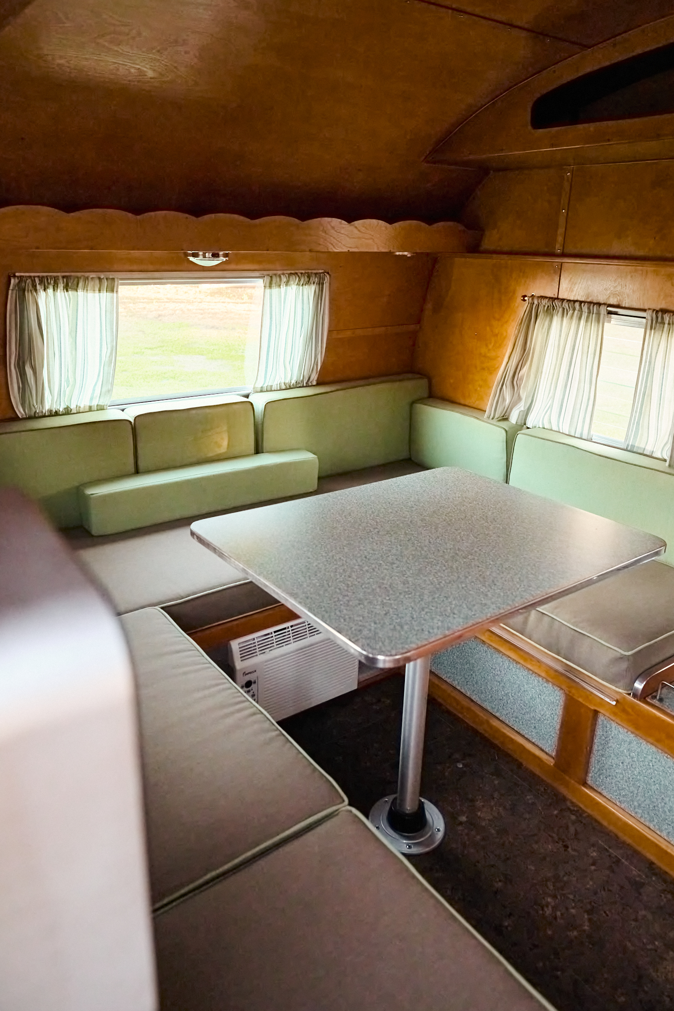 1960 Shasta Compact interior with cherry wood cabinetry and gaucho-style dining area