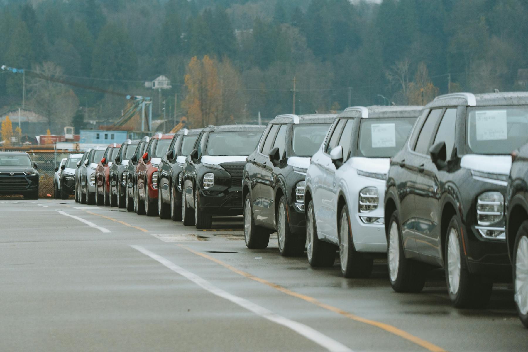 Row of new SUVs parked in a dealership lot, illustrating the dealer-floor hybrid-versus-gas trim decision