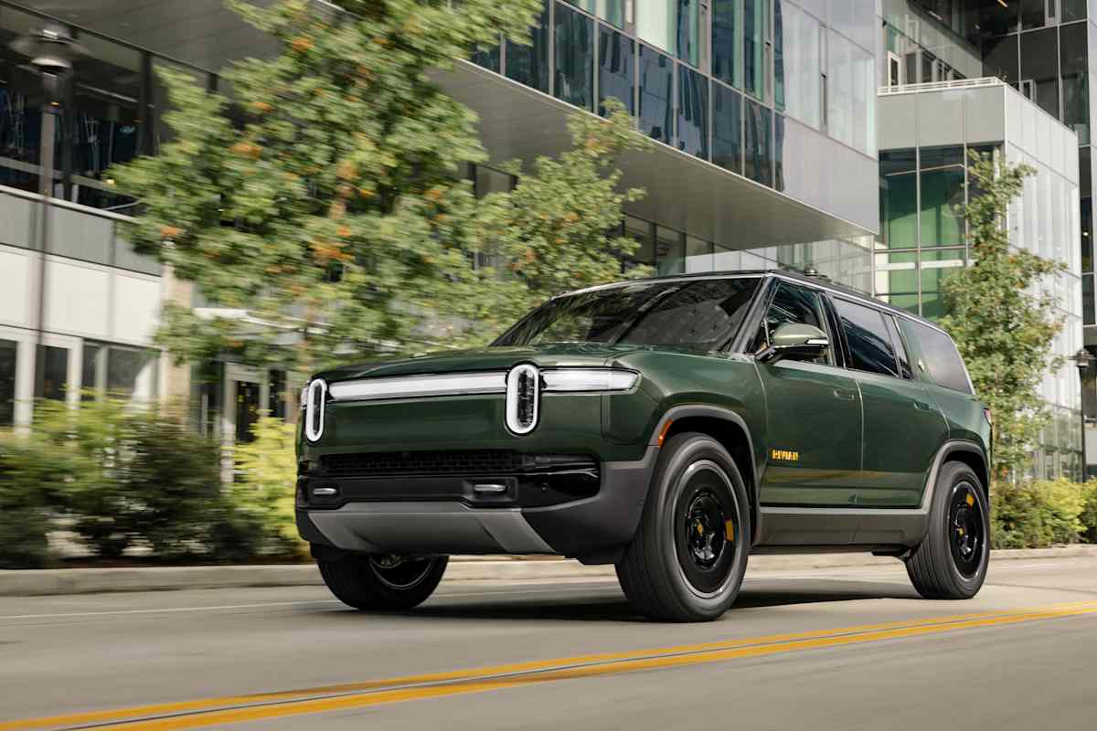 Rivian's 2026 Lineup: Every Model, Every Price, and Which One to Buy 2 2026 Rivian R1S in dark green driving through urban setting with motion blur