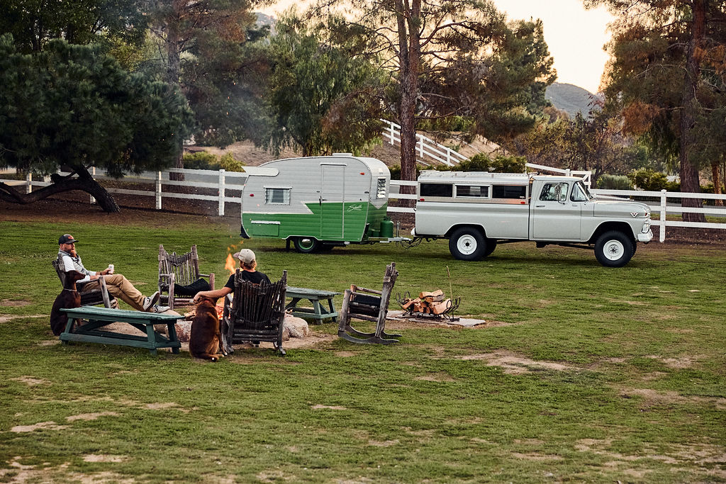 1963 GMC K1000 and 1960 Shasta camper trailer campsite setup with lawn chairs