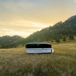Lightship AE.1 all-electric travel trailer at a remote campsite with solar panels visible on the raised roof