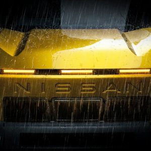 2028 Nissan Xterra teaser image showing bluff front end with stamped NISSAN wordmark in dramatic rain lighting