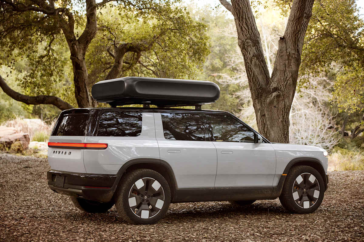 2026 Rivian R2 rear three-quarter view with rooftop cargo box in mountain setting