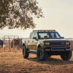 Scout Terra pickup in olive green, front three-quarter view, parked on a ranch with horses