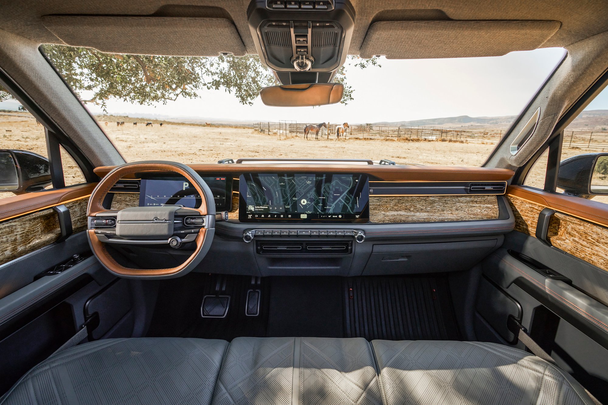 Scout Terra interior showing steering wheel, dual screens, and center console with ranch scenery through the windshield