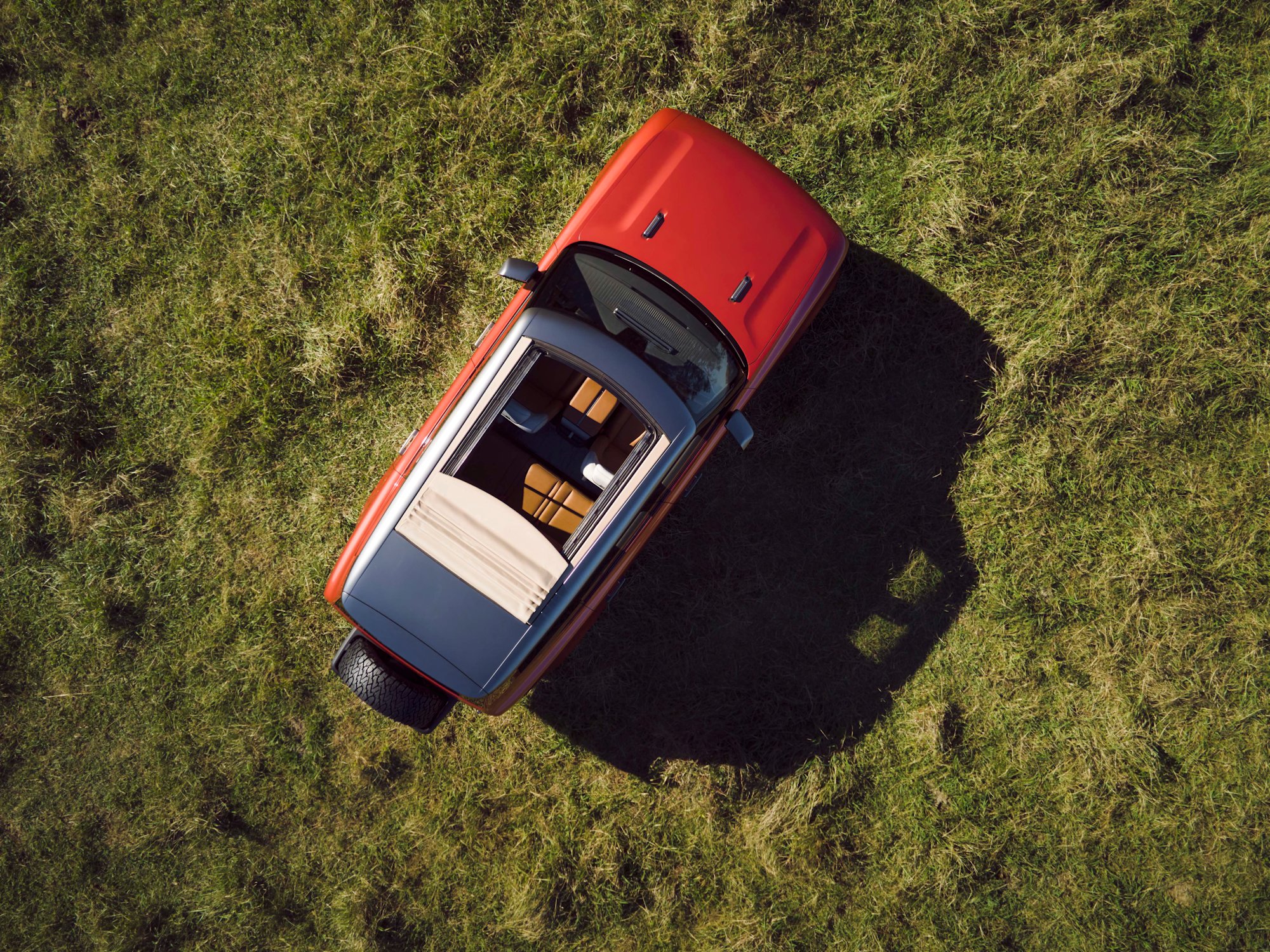 Overhead drone shot of a Scout Traveler in orange with the cabana roof panels open, parked on grass