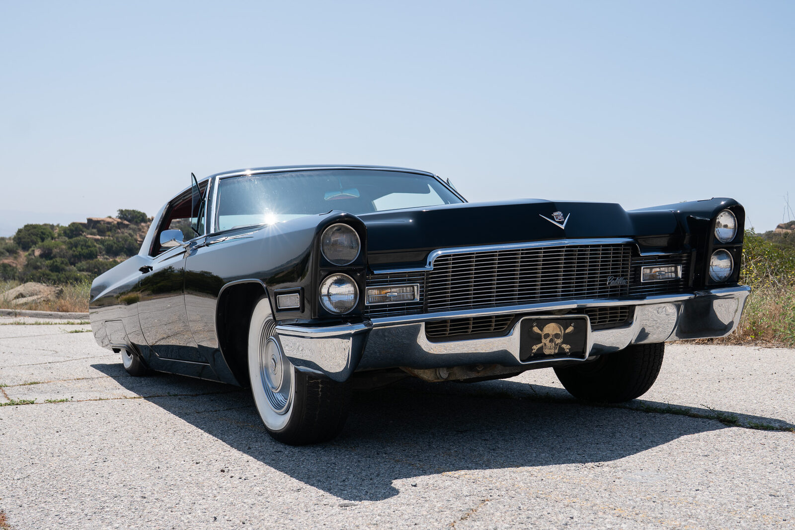 Black 1968 Cadillac Coupe DeVille front three-quarter view, lowered on its custom air suspension with the driver door open