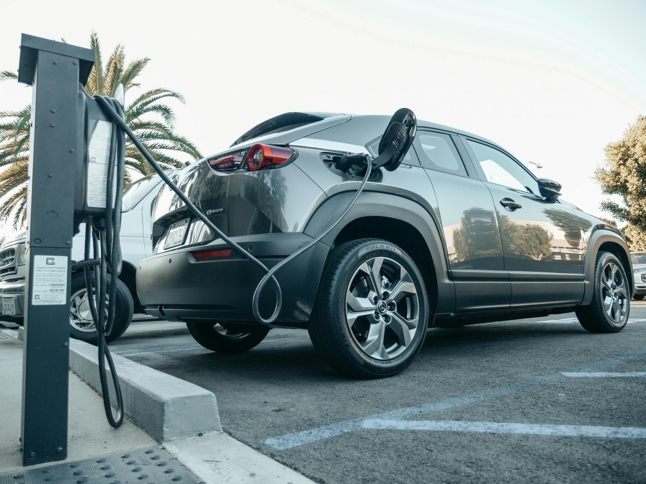 Electric vehicle plugged into a public charging station in daylight