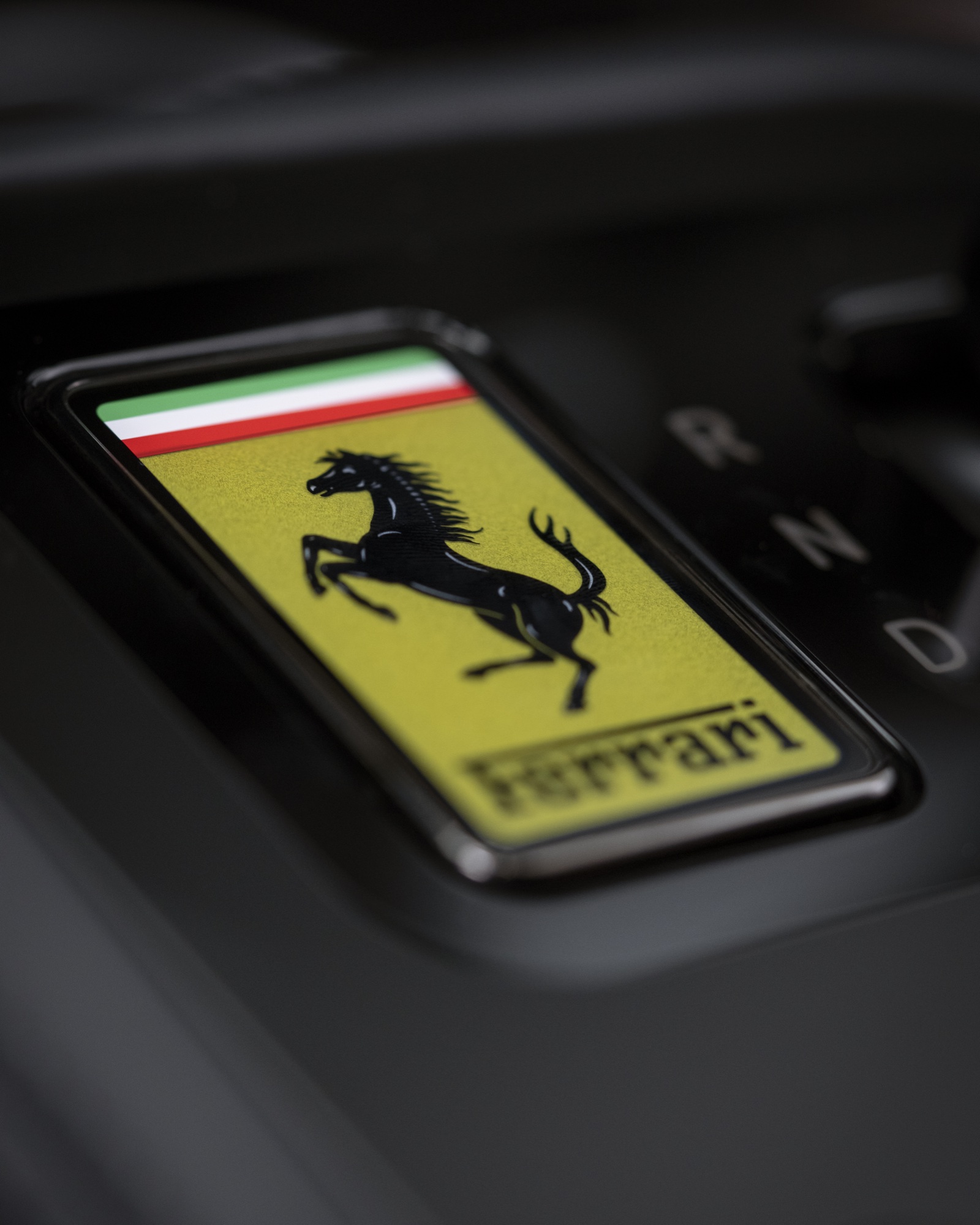 2026 Ferrari Luce gear shifter detail showing the yellow Ferrari Prancing Horse badge with R, N, and D drive positions