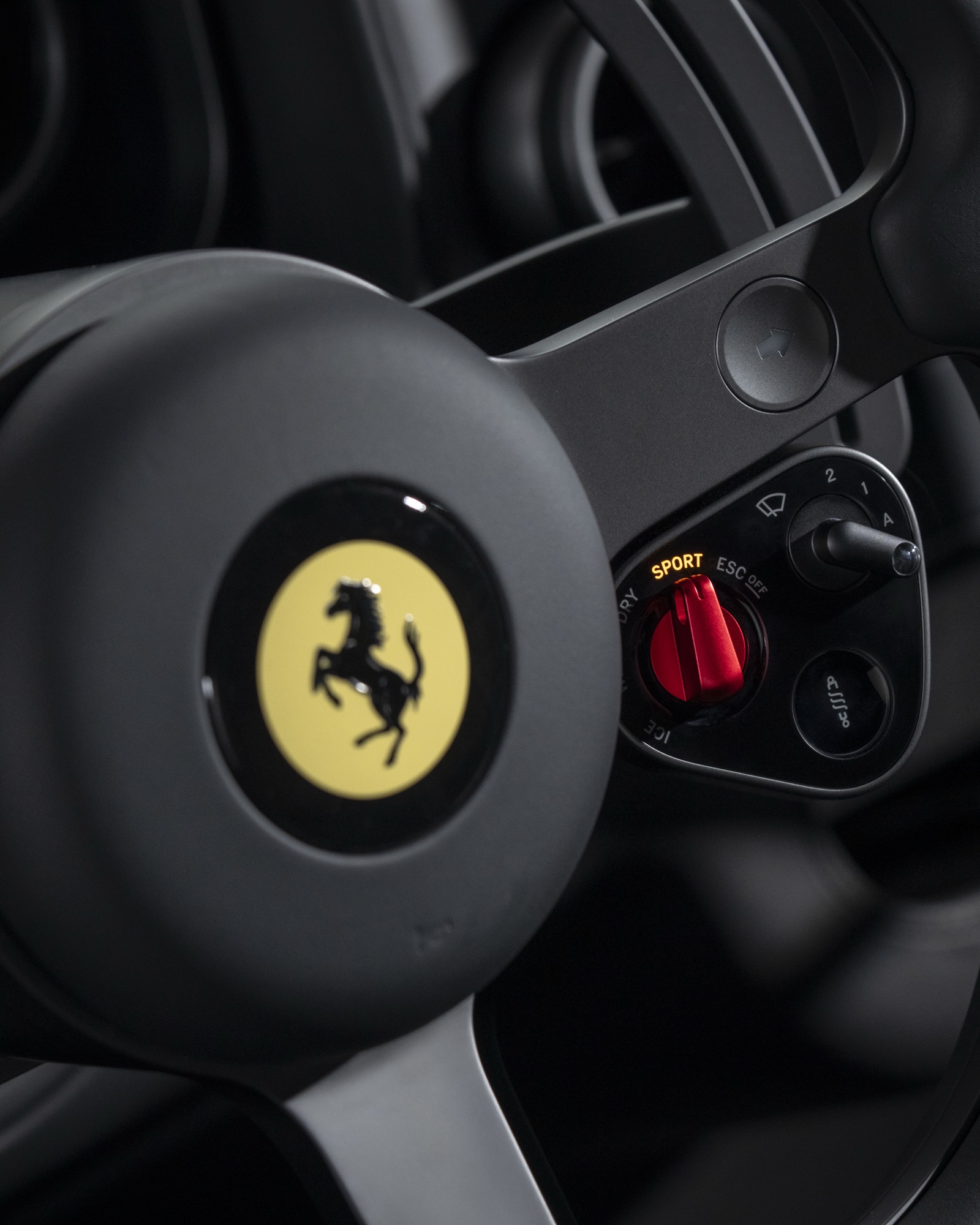 2026 Ferrari Luce steering wheel close-up showing the Ferrari Prancing Horse logo and the five-position Manettino dial set to Sport
