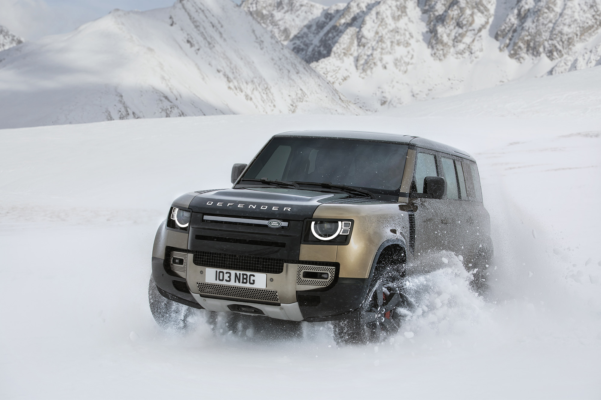 Land Rover Defender 110 in action on rocky off-road terrain, demonstrating the 40-degree departure angle and locking center differential that constitute the Defender's structural off-road advantage over the Range Rover SE