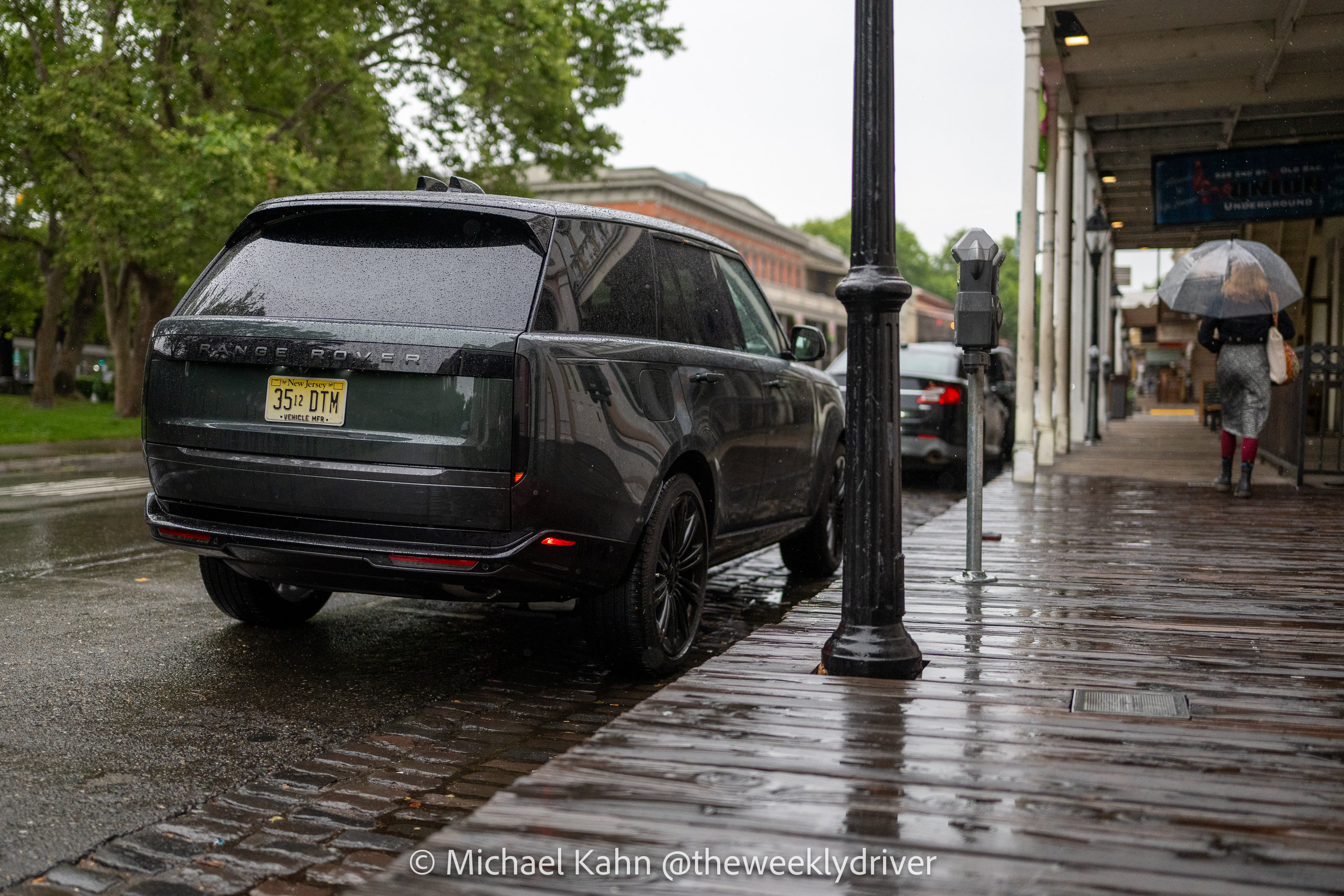 2026 Range Rover SE SWB P400 in Belgravia Green parallel parked on a rain-soaked Old Sacramento street, rear three-quarter view