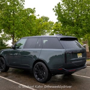 2026 Range Rover SE SWB P400 in Belgravia Green, rear three-quarter view in an office-park lot after rain, wet pavement under 23-inch gloss-black wheels