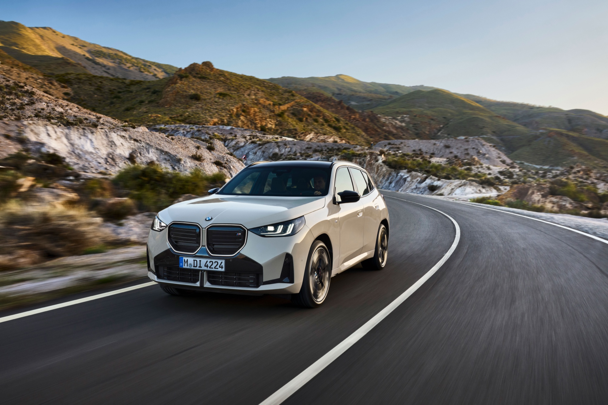A white 2025 BMW X3 driving on a mountain road, the model that helped BMW lead US luxury sales in 2026