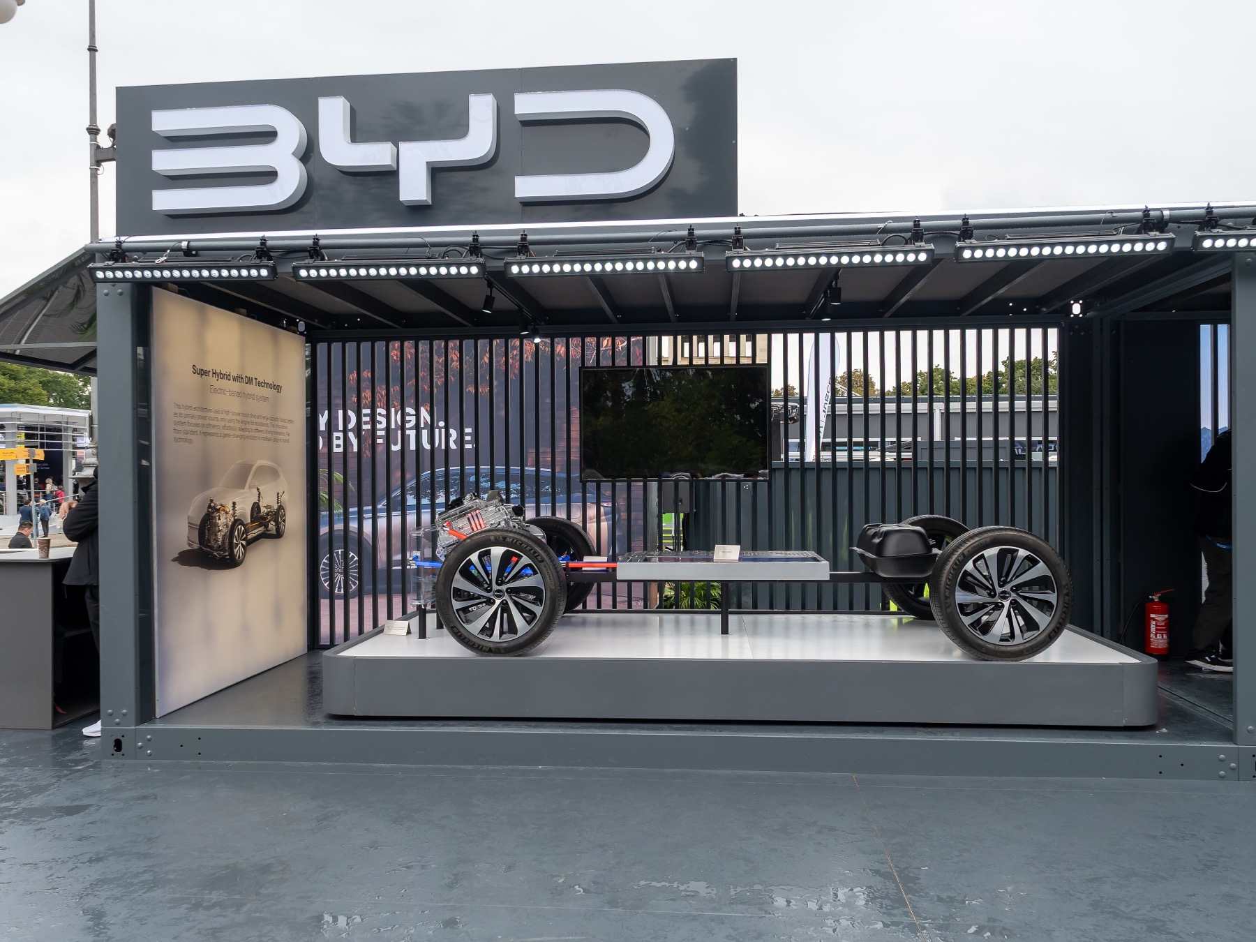 A BYD outdoor exhibition stand displaying a plug-in hybrid chassis with engine and battery pack at Koenigsplatz in Munich
