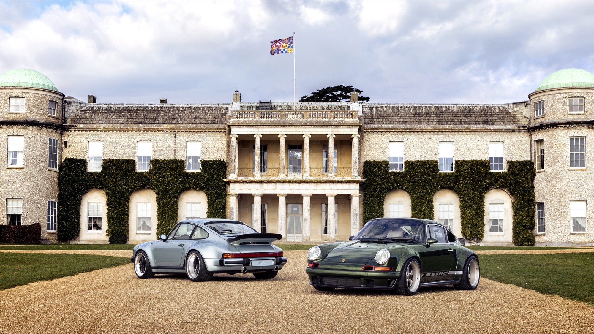 Two Porsche 911s reimagined by Singer parked in front of Goodwood House