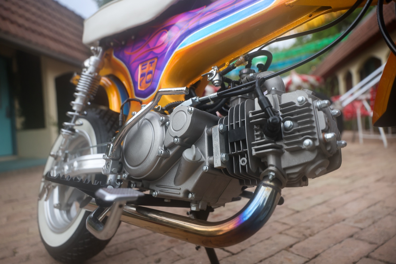 The 125cc four-speed engine and chrome drag-pipe exhaust on the Hemmings Stay Gold custom CT-70 minibike, with the gold metal-flake and purple flame paint above