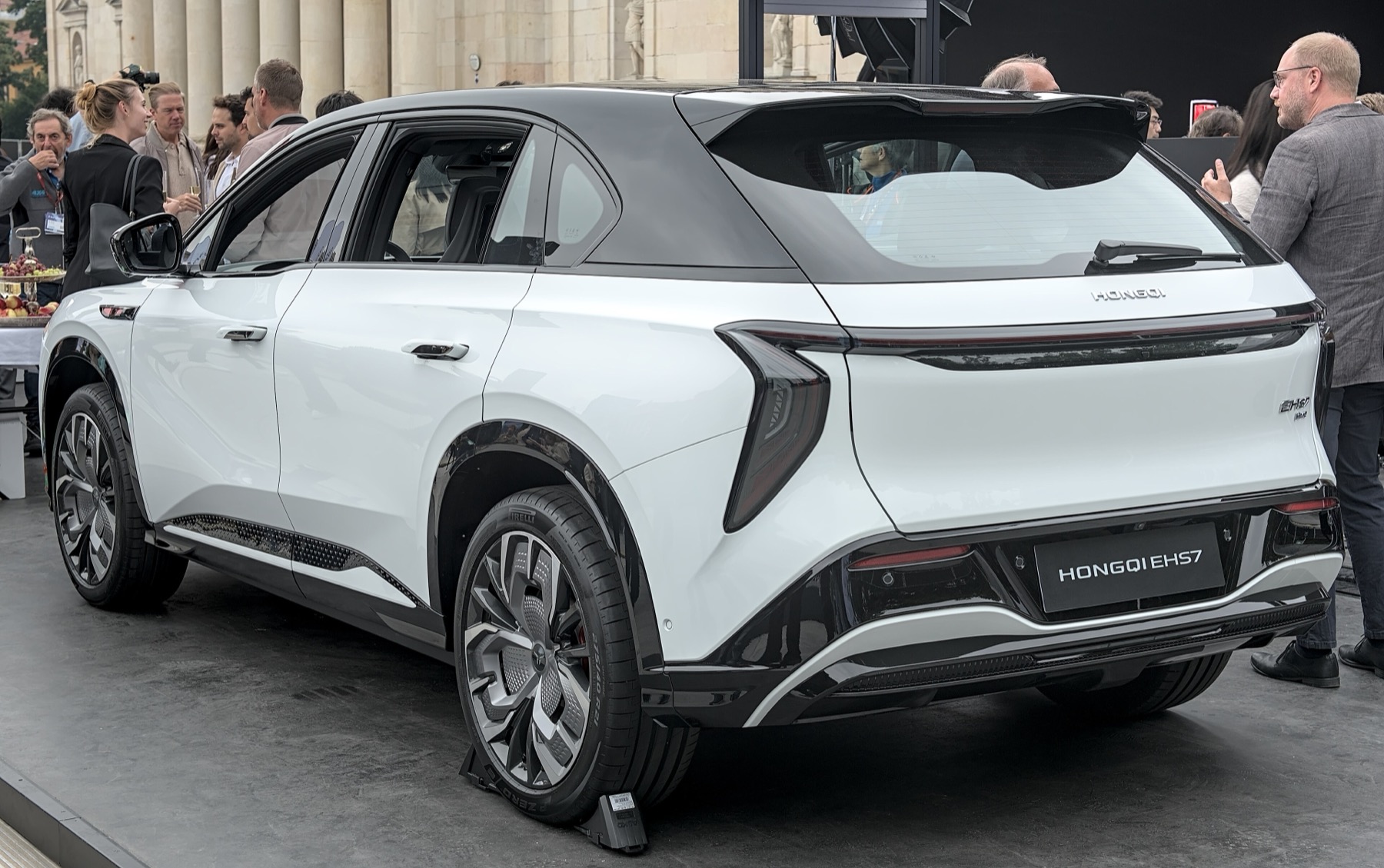 A white Hongqi EHS7 electric SUV on display surrounded by visitors at a European motor show