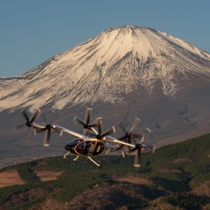 Toyota and Joby Aviation S4 all-electric air taxi in flight past a snow-capped Mount Fuji, six rotors spinning in cruise configuration