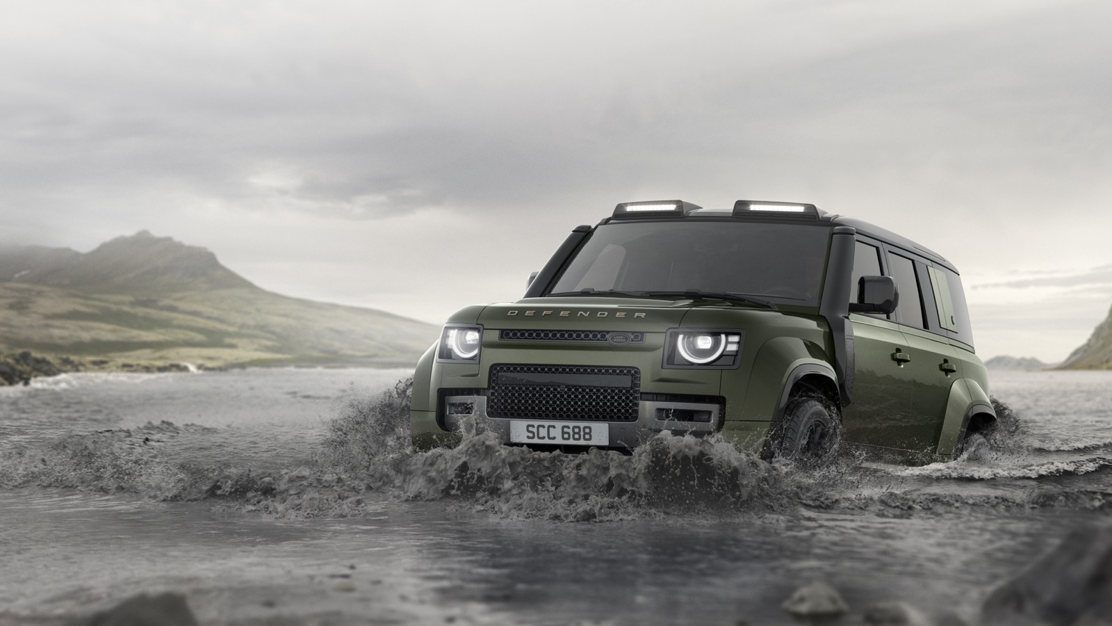 2027 Land Rover Defender Octa in Woolstone Green fording a river, showing the raised off-road suspension and roof light bar