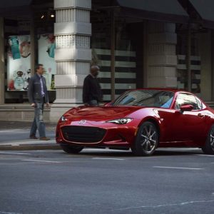 Red Mazda MX-5 Miata RF front three-quarter on a city street, the current ND generation