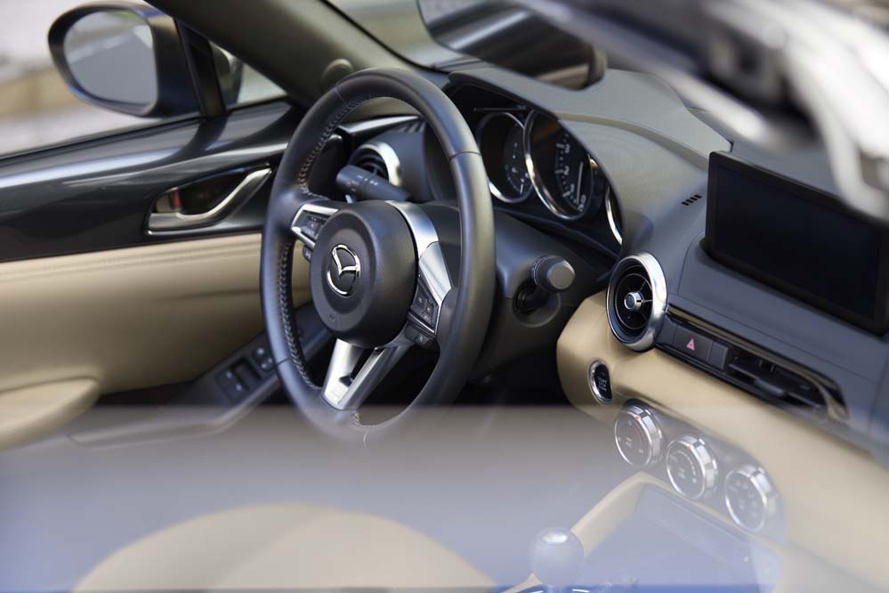 Mazda MX-5 Miata interior showing the manual gearshift, analog gauges, and driver-focused dashboard