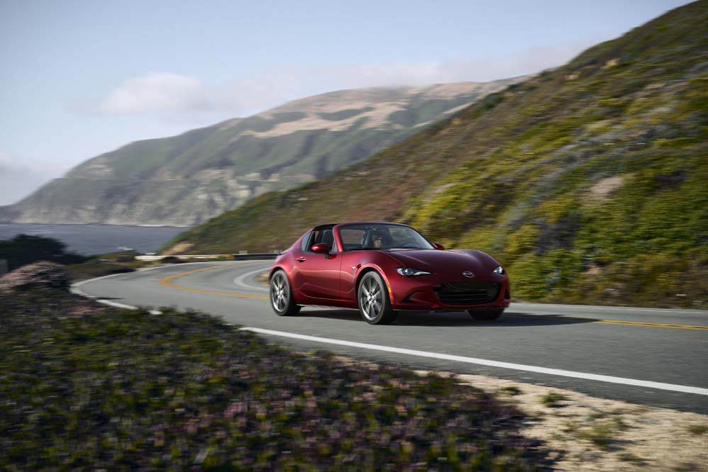 Red Mazda MX-5 Miata RF on a coastal mountain road, current ND generation