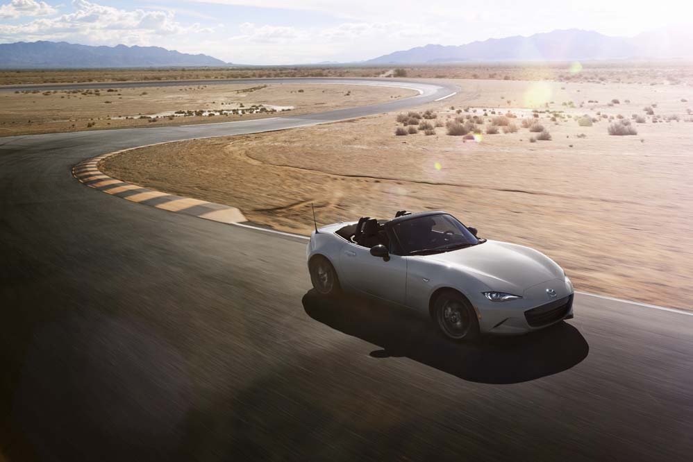 Silver Mazda MX-5 Miata soft-top with the roof down on a desert road, current ND generation