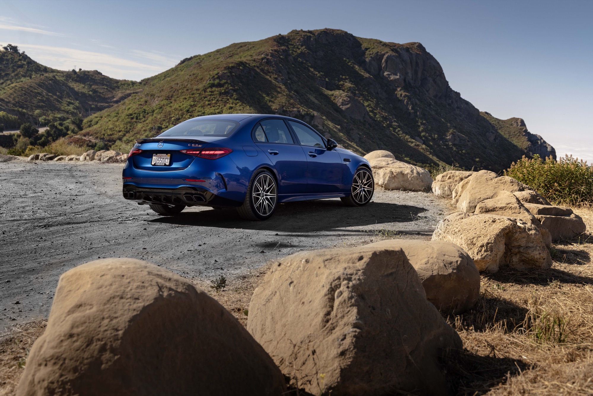 A blue Mercedes-AMG C 63 S E Performance seen from the rear three-quarter on a mountain road