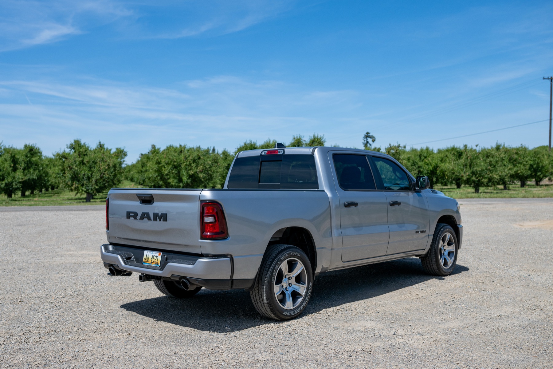2026 RAM 1500 Express Crew Cab 4x2 rear three-quarter view in an orchard