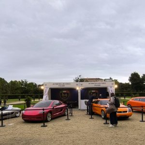 A row of concept cars displayed on gravel in the Giardini Reali in Turin during Salone Auto Torino, with the Palazzo Reale behind