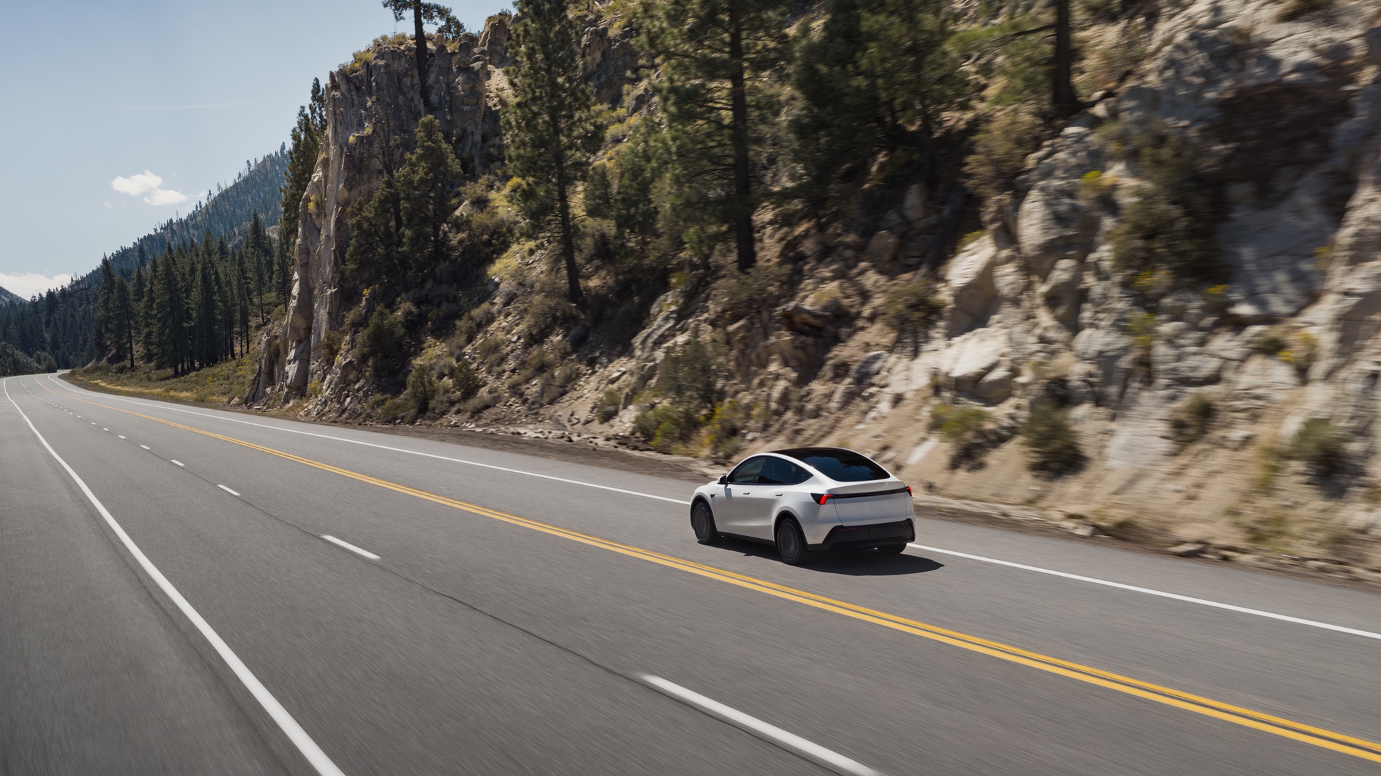 A 2026 Tesla Model Y on a highway beside a canyon wall
