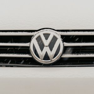 A snow-dusted Volkswagen badge on a car grille, representing the group's 2030 restructuring plan to cut its model lineup