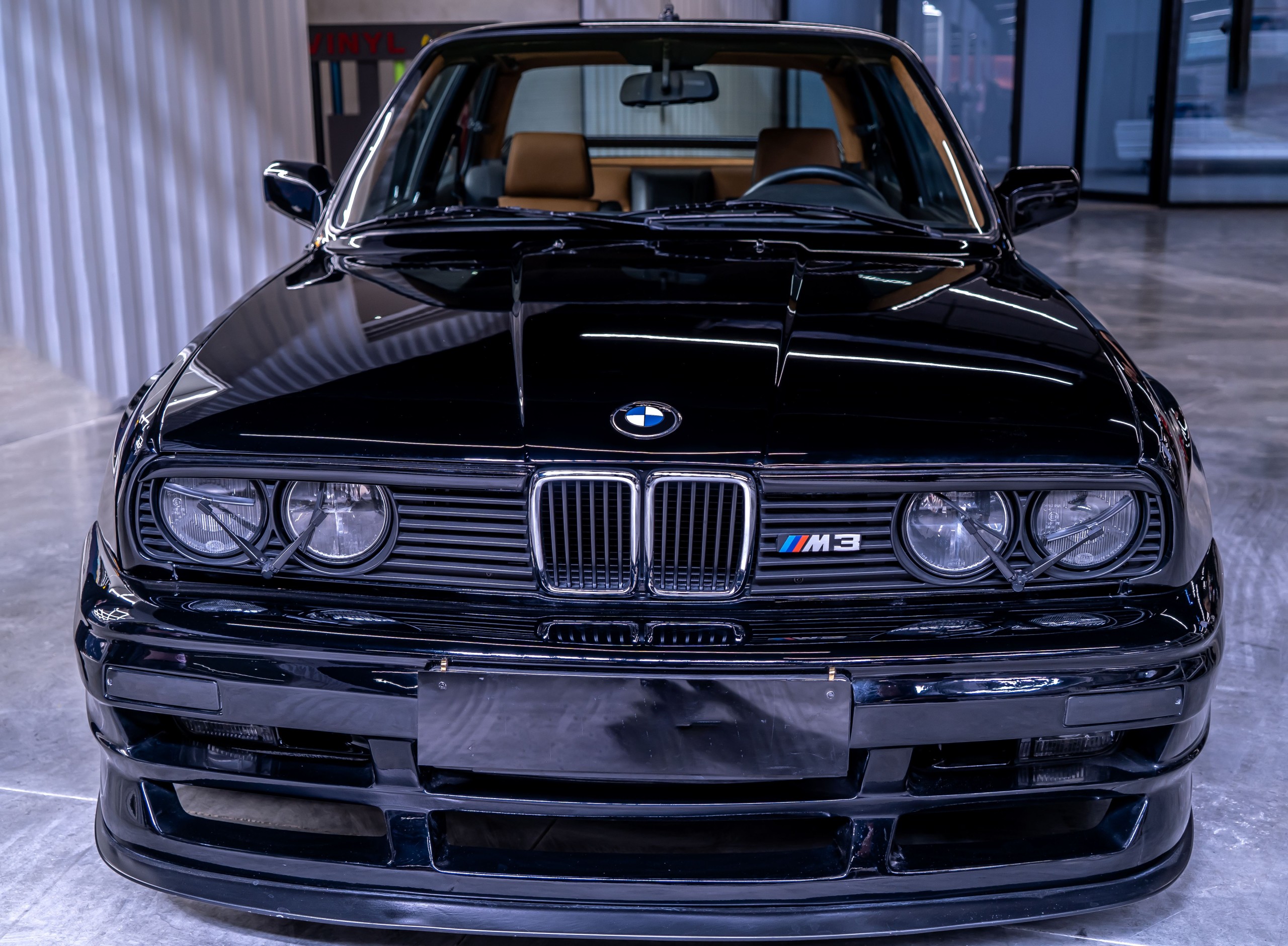 Front view of a classic BMW E30 M3 in dark paint