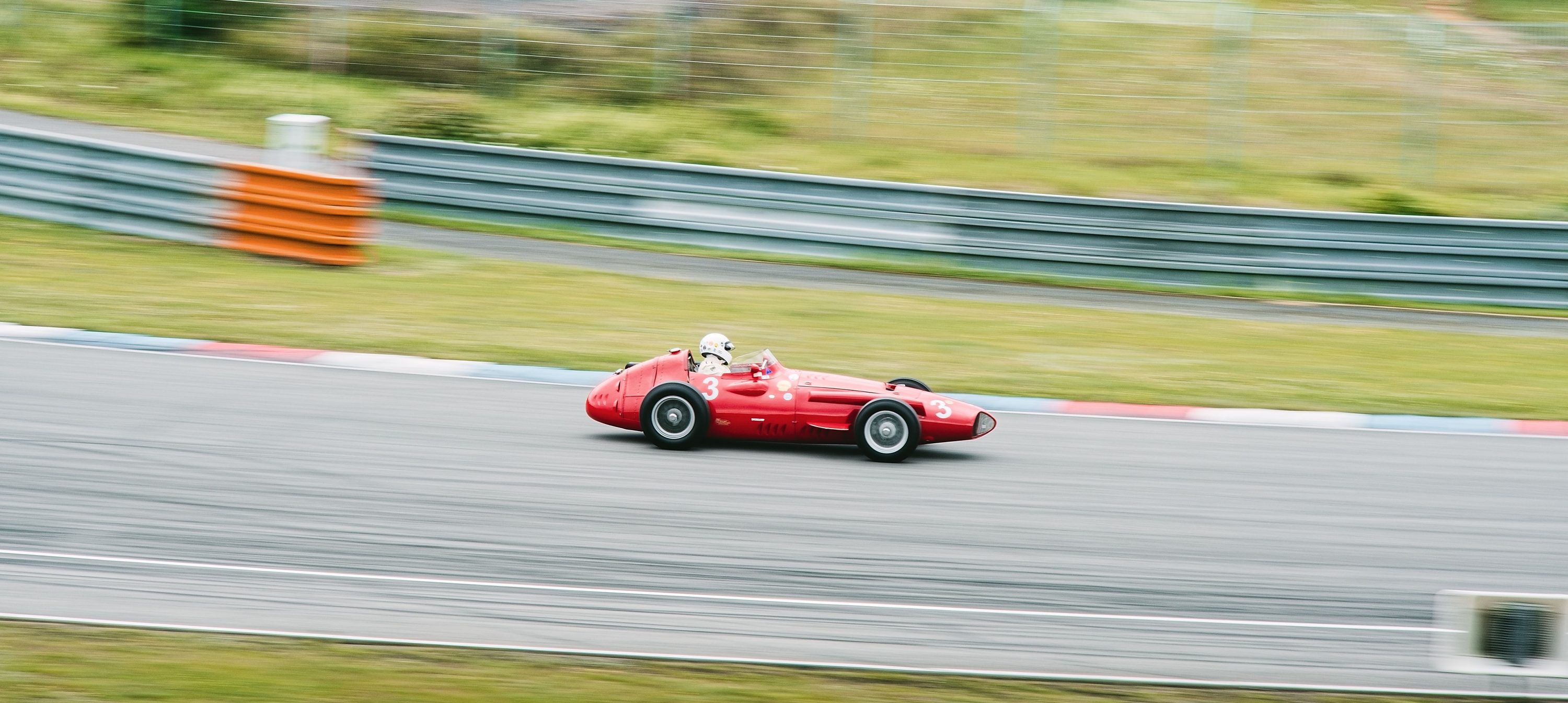 Classic red race car at speed on a circuit