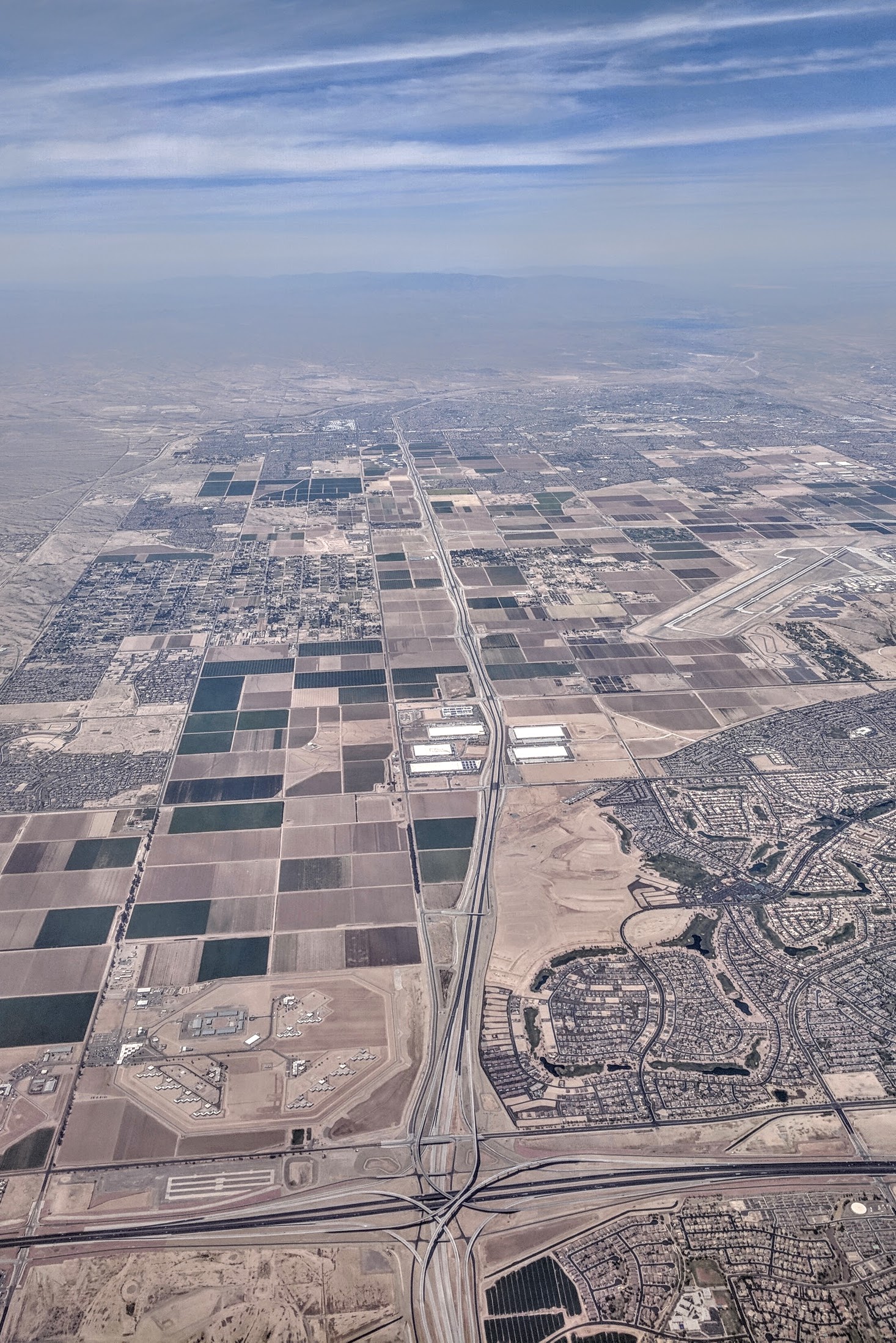 Arizona’s Fastest-Growing Suburbs Are Outrunning Their Roads — Here’s What the Crash Data Shows 6 Aerial view of the Loop 303 and Interstate 10 stack interchange at Goodyear, Arizona, with distribution warehouses, irrigated farm fields and new subdivisions surrounding the corridor