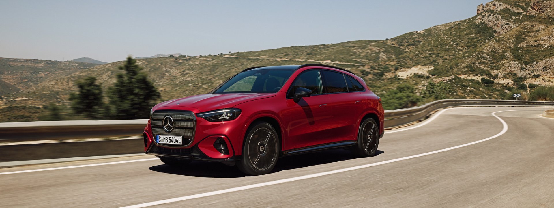 Red all-new electric Mercedes-Benz GLC driving on a coastal mountain road, front three-quarter view