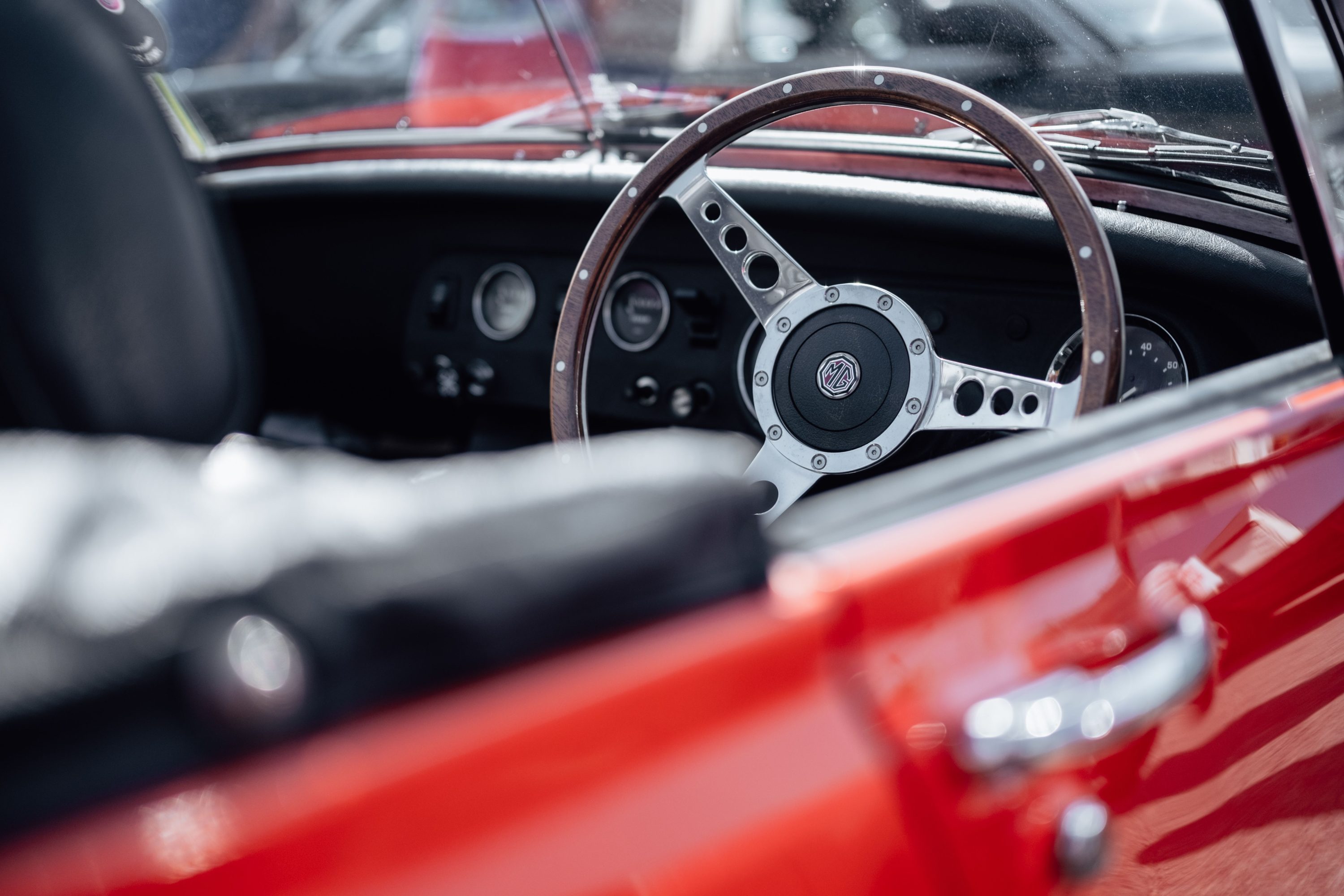 Close-up of a classic roadster interior showing a wooden steering wheel and dashboard