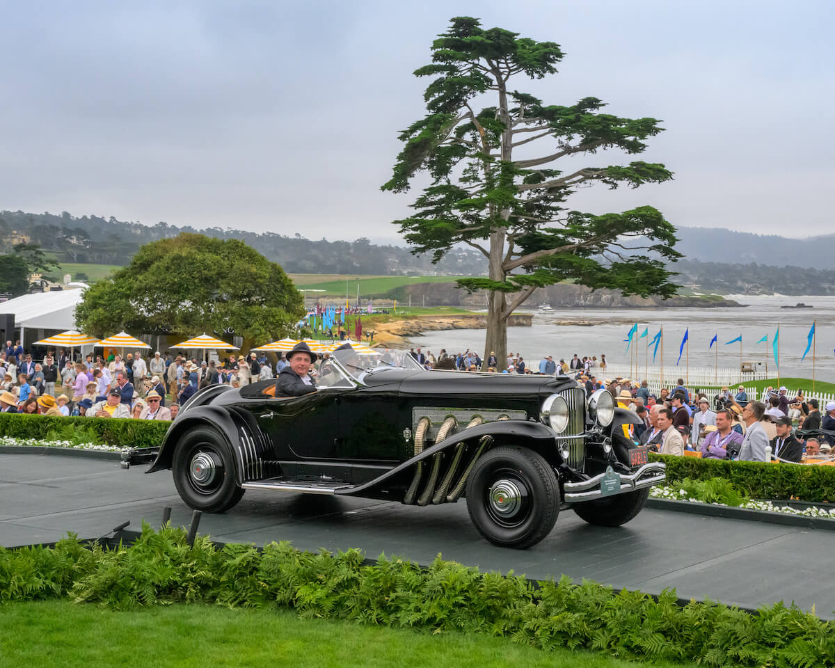 Black 1935 Duesenberg SSJ Special Speedster in profile on the Pebble Beach awards ramp above Carmel Bay